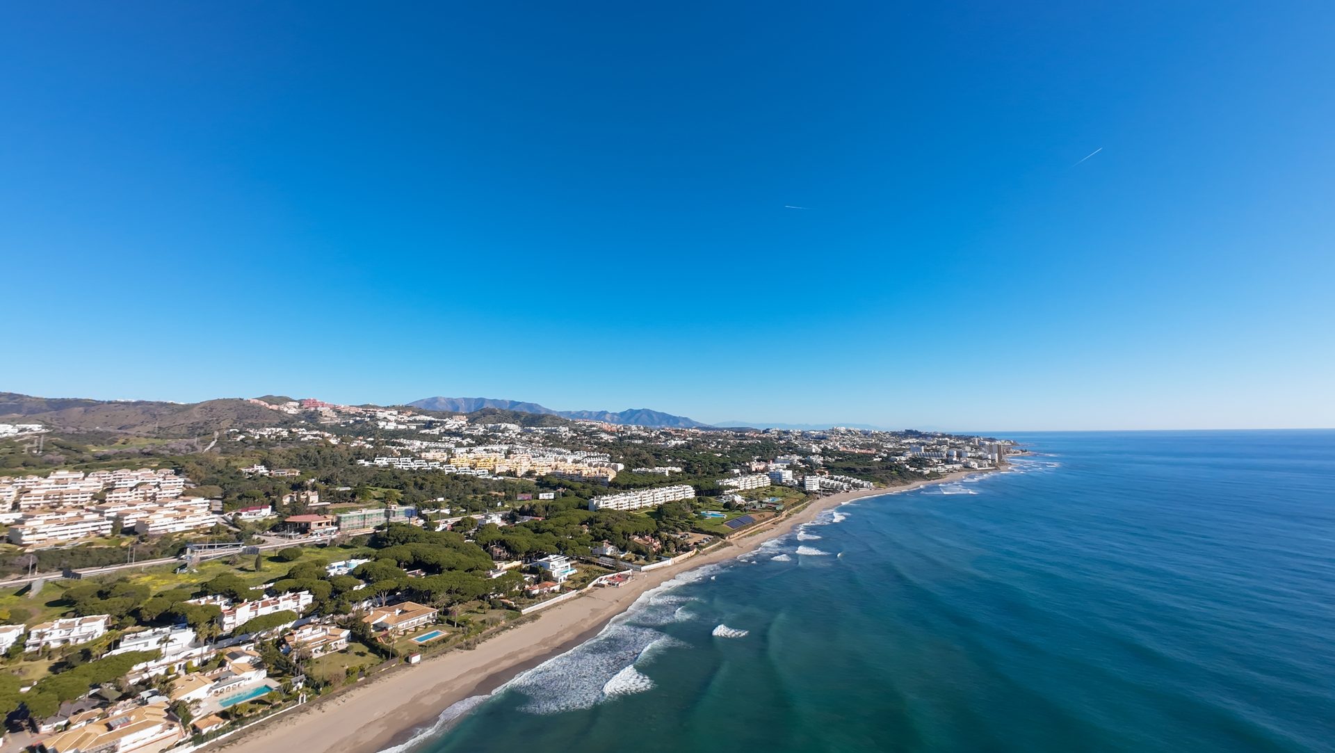Aerial view of a coastal town with a beach and clear blue sky.